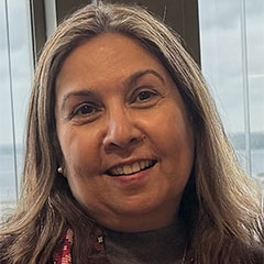 Headshot of Dr. Ayesha Mirza, smiling, with long light brown hair, in an office setting