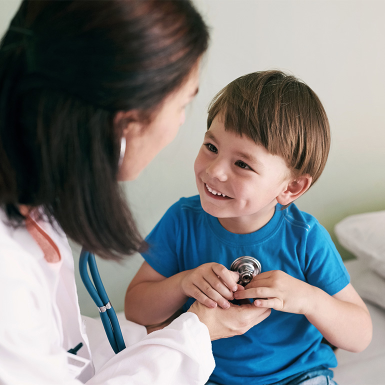 Doctor checking a happy child's heart with a stethoscope.