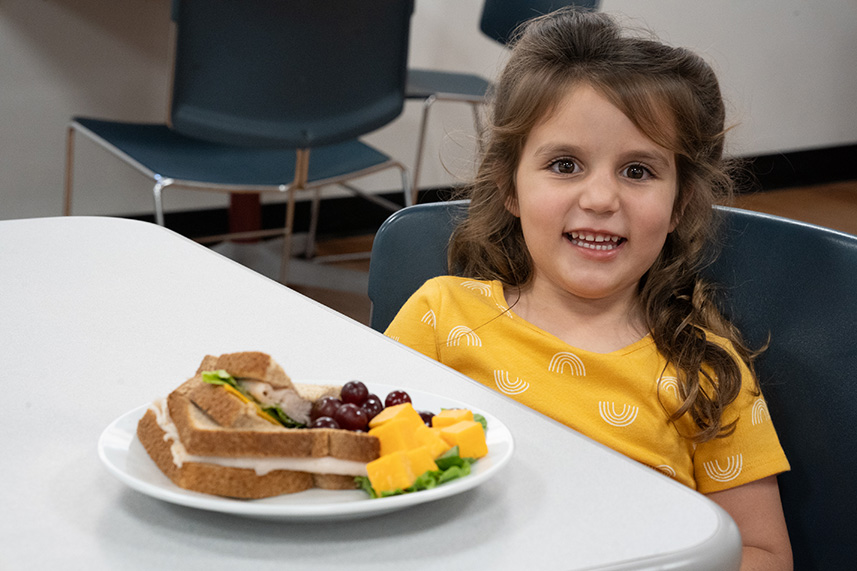Toddler girl at a table with healthy lunch.